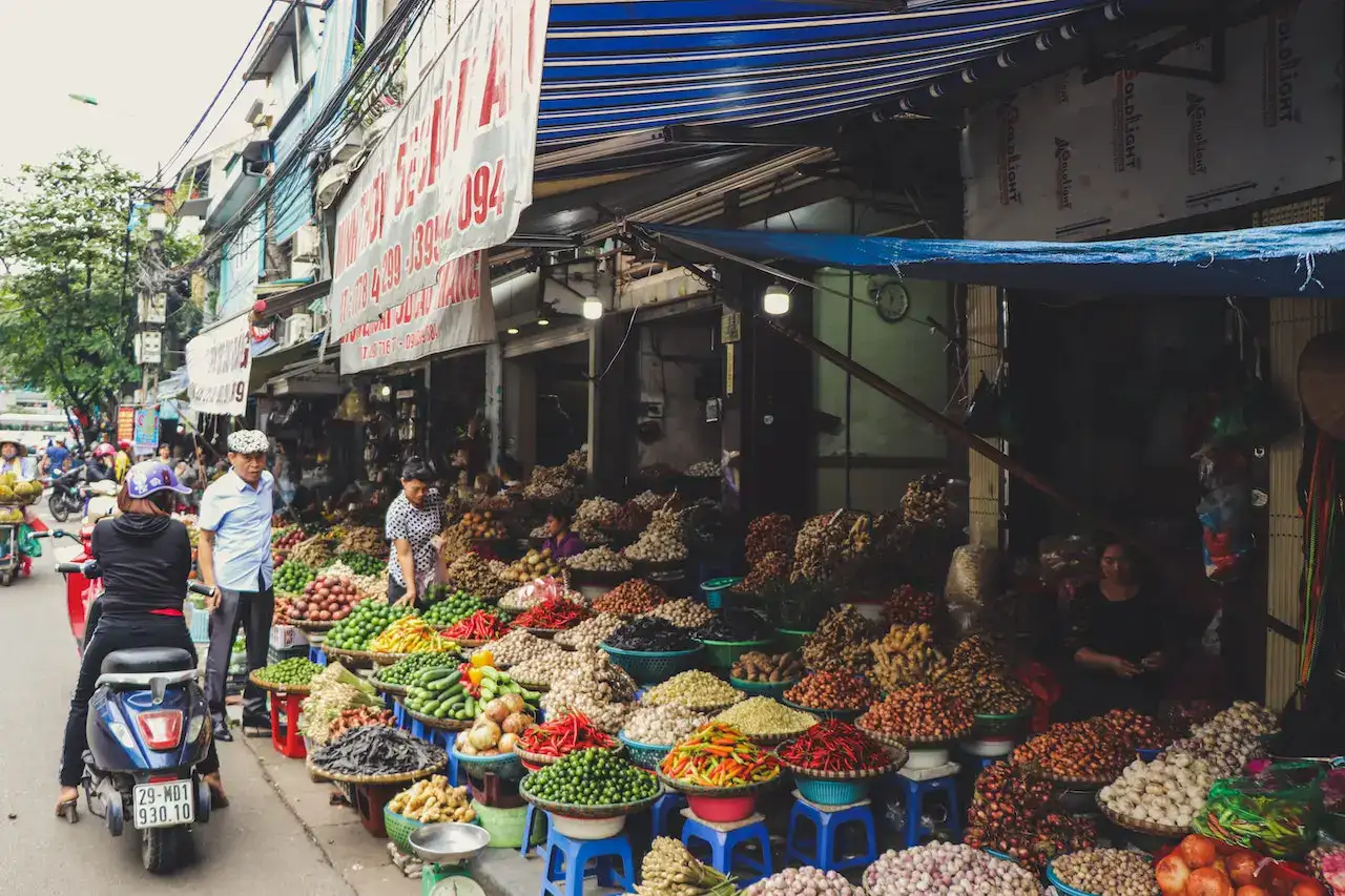 Street-level view of a vibrant Vietnamese vegetable market.